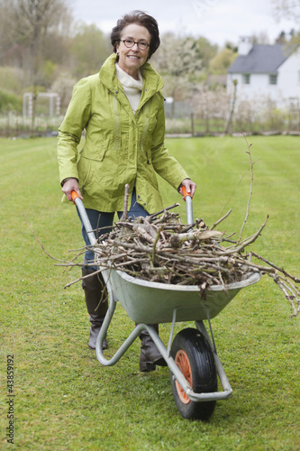 Photo: Woman pushing a wheelbarrow full of branches Woman pushing a wheelbarrow full of branches