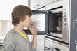 Teenage boy looking into an oven with surprise