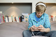 Teenage boy listening to music on iPod at home