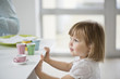 Foto: Cute girl with toy tea set near a dining table Cute girl with toy tea set near a dining table