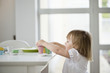 Foto: Cute little girl picking up toy tea set from a dining table Cute little girl picking up toy tea set from a dining table