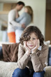 Boy sitting on a couch with his parents romancing in the background