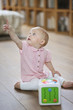 Baby girl sitting on the floor and pointing away with finger