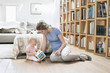 Woman sitting near her daughter playing with a toy