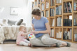 Woman sitting near her daughter playing with a toy