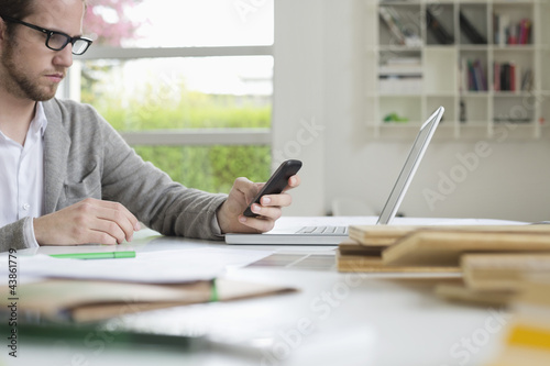 Photo: Interior designer using a mobile phone in the office Interior designer using a mobile phone in the office