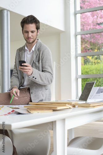 Photo: Interior designer using a mobile phone in the office Interior designer using a mobile phone in the office