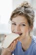 Portrait of a woman eating toast with cream spread on it