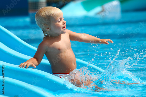 Photo: Child on water slide at aquapark. Child on water slide at aquapark.