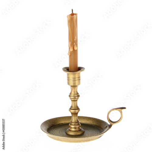 Photo: Candle on the old brass candlesticks on a white background. Candle on the old brass candlesticks on a white background.