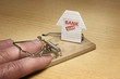 Hand of man caught in mousetrap set by the bank
