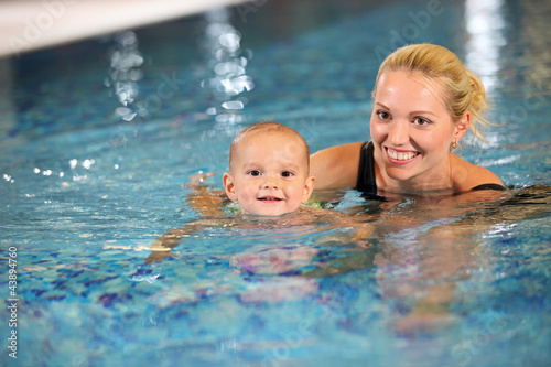 Photo: Young cheerful mother and little son in a swimming pool Young cheerful mother and little son in a swimming pool