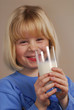 Niña feliz bebiendo un vaso de leche.