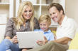 Happy Family Sitting on Sofa Using Laptop Computer