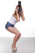 Cheerful woman shooting with a camera against white background