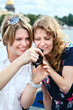 Photo: Two beauty women looking at screen of simple hand-held camera Two beauty women looking at screen of simple hand-held camera