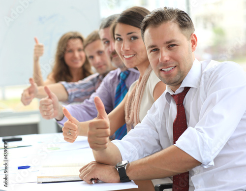 Photo: Businessteam with thumbs up after a presentation in office Businessteam with thumbs up after a presentation in office