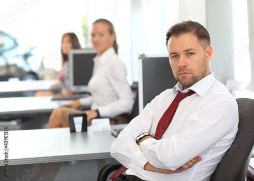 Photo: Businessman sitting at desk using computer with colleagues Businessman sitting at desk using computer with colleagues