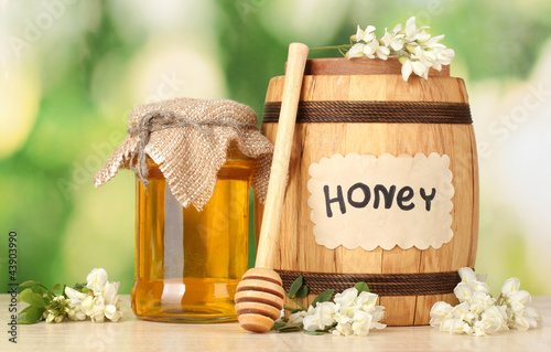 Photo: Sweet honey in barrel and jar with acacia flowers Sweet honey in barrel and jar with acacia flowers