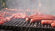 Outdoor meat grilling on barbecue with people in background