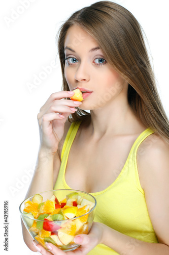 Photo: Portrait of a young woman eating fruit salad isolated on a white Portrait of a young woman eating fruit salad isolated on a white