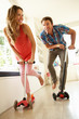 Couple Riding Childrens Scooters Indoors