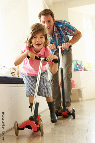 Photo: Father And Son Riding Scooters Indoors Father And Son Riding Scooters Indoors