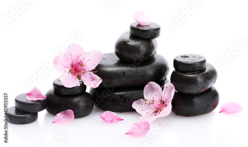 Photo: Spa stones with drops and pink sakura flowers isolated on Spa stones with drops and pink sakura flowers isolated on