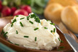 Fresh cream cheese spread on wooden plate with chives