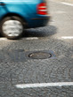 a car passing manhole cover on a paved road