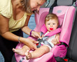 Photo: Woman fastening her son on a baby seat in a car Woman fastening her son on a baby seat in a car