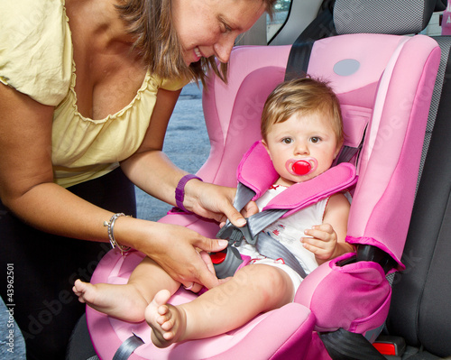 Photo: Woman fastening her son on a baby seat in a car Woman fastening her son on a baby seat in a car