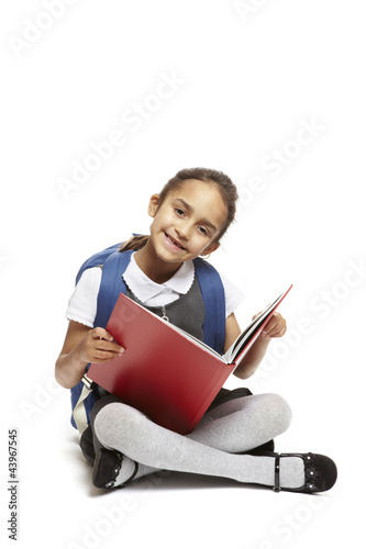 Photo: 8 year old school girl sitting reading book on white background 8 year old school girl sitting reading book on white background