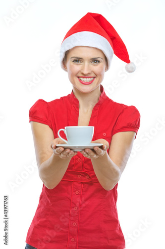 Photo: Happy woman in Christmas hat holding cup of hot beverage Happy woman in Christmas hat holding cup of hot beverage