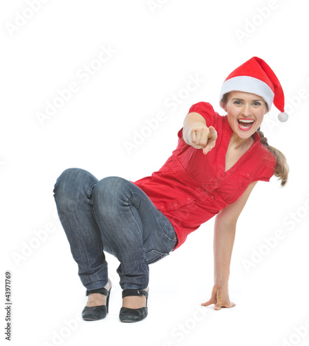 Foto: Happy woman in Christmas hat squatted on floor and pointing in c Happy woman in Christmas hat squatted on floor and pointing in c