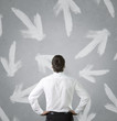 Businessman looking at arrows pointed in different directions