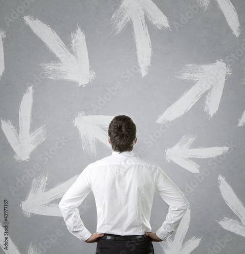 Foto: Businessman looking at arrows pointed in different directions Businessman looking at arrows pointed in different directions
