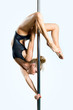 Young sexy woman exercise pole dance against a gray background