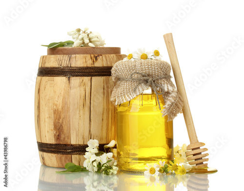 Photo: Sweet honey in barrel and jar with acacia flowers isolated Sweet honey in barrel and jar with acacia flowers isolated