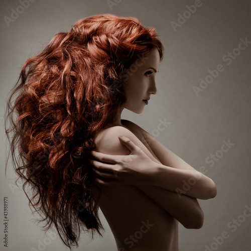 Photo: Beautiful woman with curly hairstyle against gray background Beautiful woman with curly hairstyle against gray background