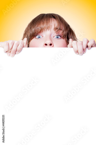 Photo: Woman peeking over a blank white placard Woman peeking over a blank white placard