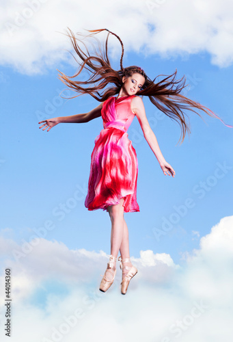 Foto: Ballerina dancing on the roof, clouds behind her Ballerina dancing on the roof, clouds behind her