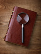 Notebook with a magnifier on wood table