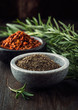 Black pepper in bowl; chili flakes and rosemary in background