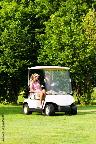 Foto: Junges sportliches Paar mit Golfcart am Golfplatz Junges sportliches Paar mit Golfcart am Golfplatz