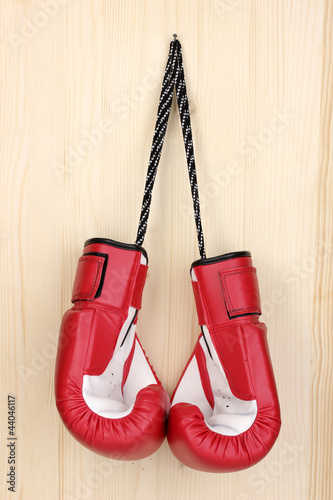 Photo: Red boxing gloves hanging on wooden background Red boxing gloves hanging on wooden background