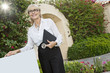 Photo: Happy senior woman standing by sign board with clipboard Happy senior woman standing by sign board with clipboard