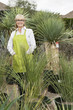 Portrait of a senior female gardener surrounded by potted plants