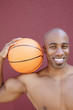Photo: Portrait of a happy African American man with basketball on shoulder over colored background Portrait of a happy African American man with basketball on shoulder over colored background