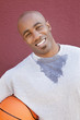 Photo: Portrait of a happy young African American man with basketball over colored background Portrait of a happy young African American man with basketball over colored background